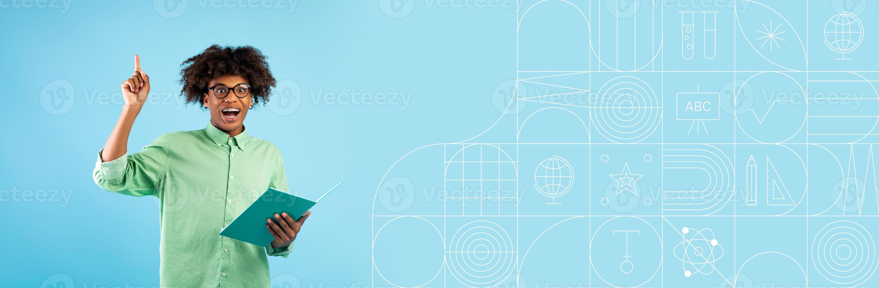 A student with an excited expression holds a notebook while pointing upwards, indicating a moment of insight. photo