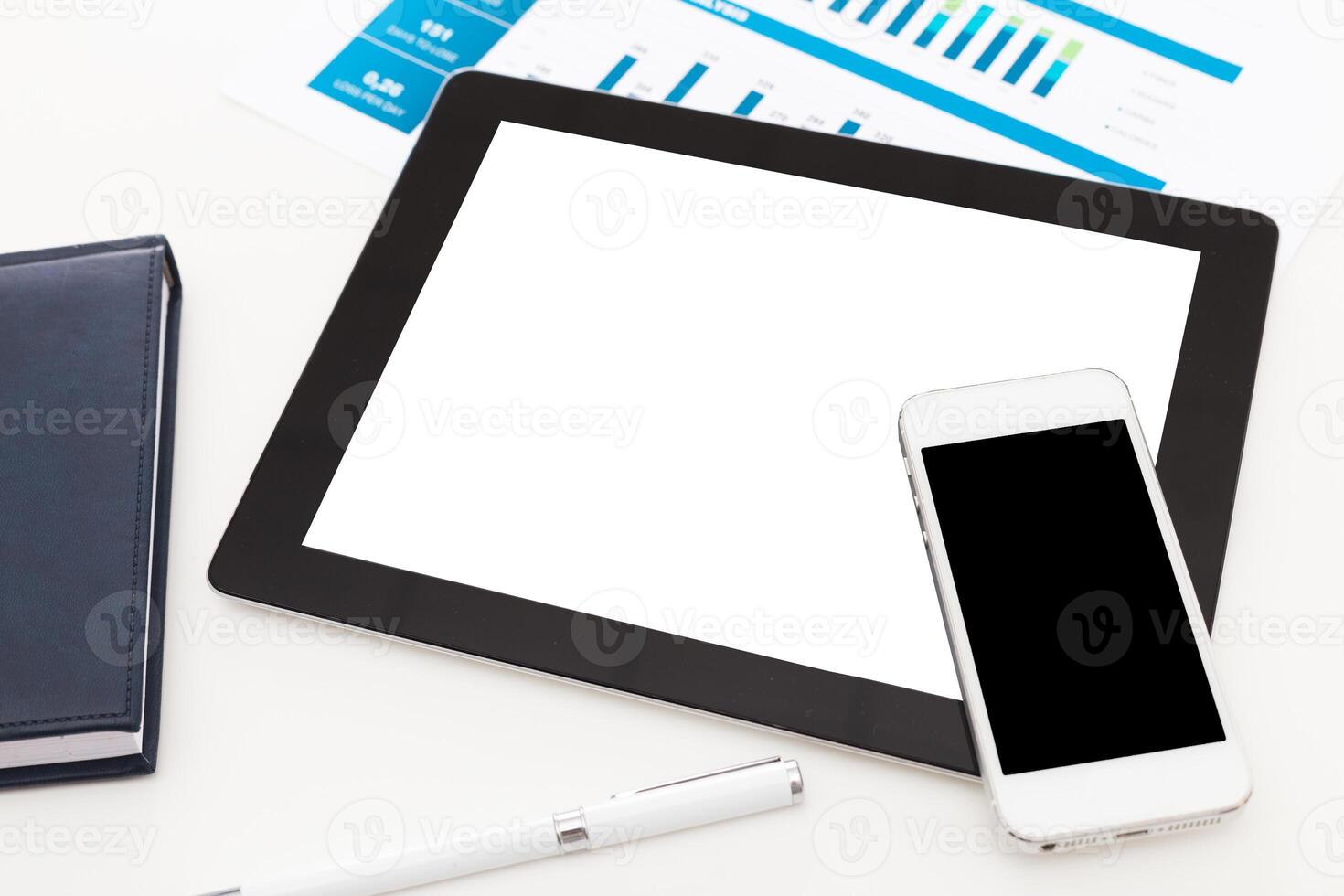 Workspace setup with tablet, smartphone, and documents showcasing data analysis photo