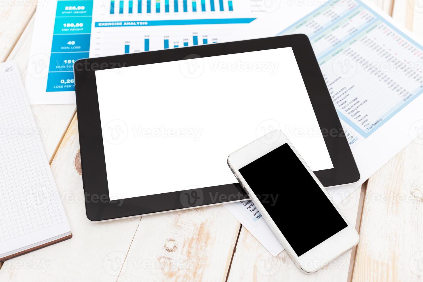 Working on digital devices with analysis reports on a desk in an office environment photo