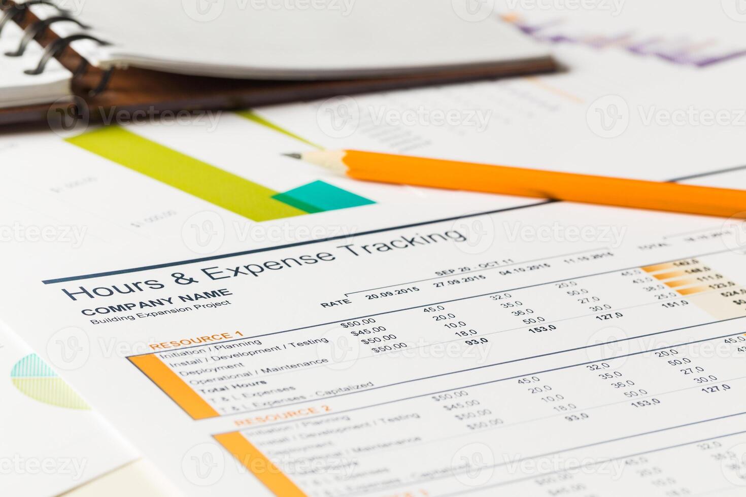 Expense tracking and project management sheets on a workspace table with a notebook photo