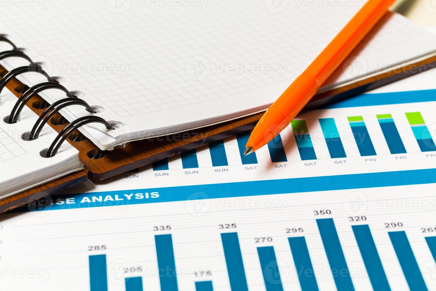 Data analysis in progress with graphs and a notepad lying on a table photo