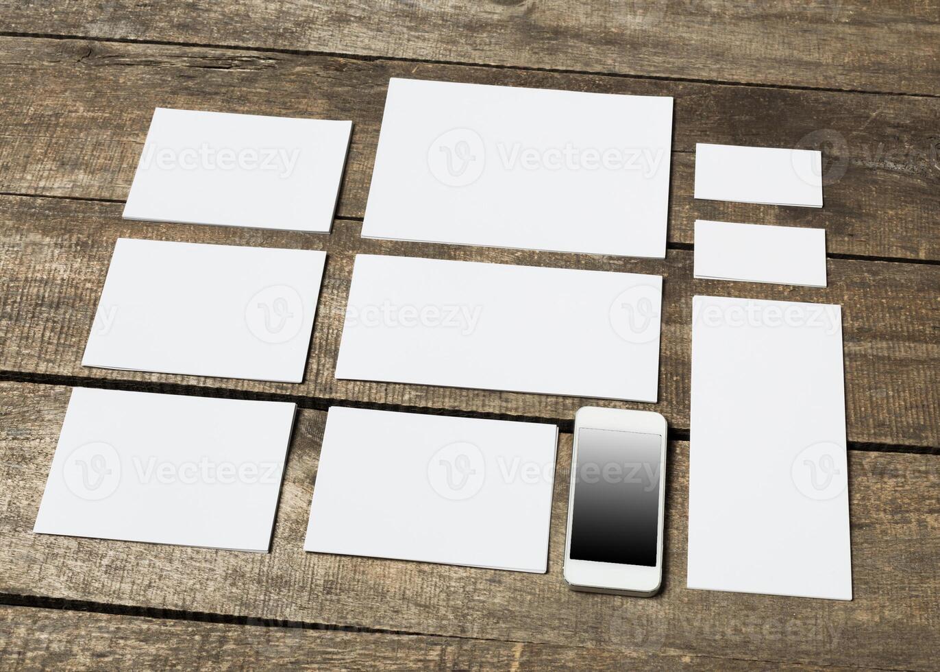 Collection of blank rectangular paper sheets and a smartphone on a wooden surface photo