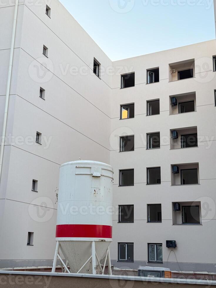 Courtyard of modern building with windows and cylindrical container. Architecture, construction, and urban residential development with exterior structural elements. photo