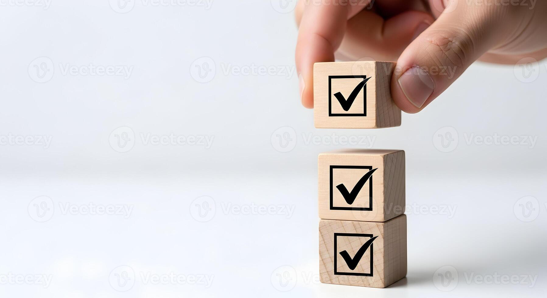 Hand placing wooden block with check mark on top of a stack of similar blocks against a white background, symbolizing task completion, goals, and success photo