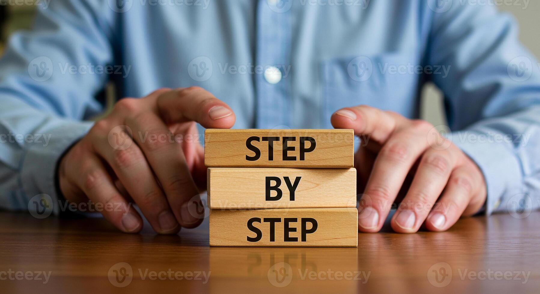 Man arranging wooden blocks spelling out Step by Step on a desk illustrating a process strategy or plan The image conveys concepts of planning process methodology and step-by-step guidance photo