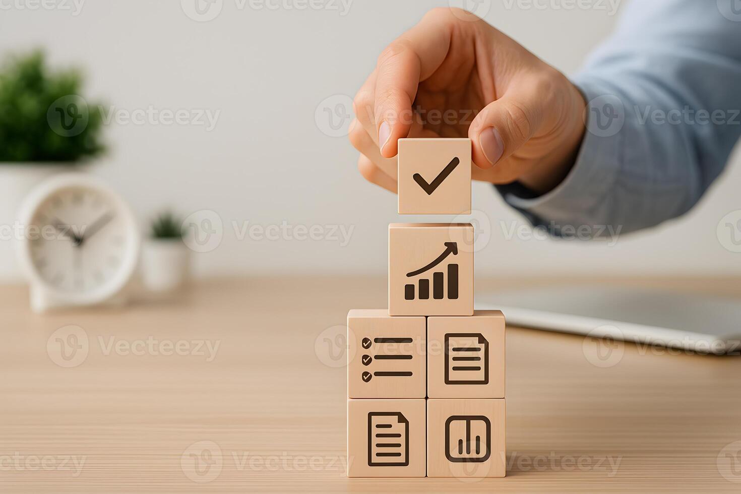 Hand placing a checklist block on a stack of wooden blocks with growth chart documents and planning icons representing business strategy and success on a modern office desk photo