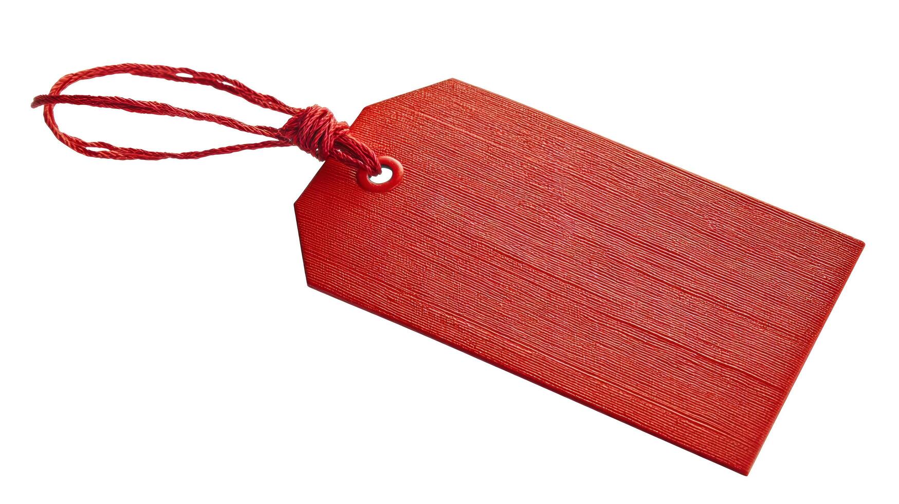 A single red tag with a string attached to it laying on a white surface in a studio setting photo