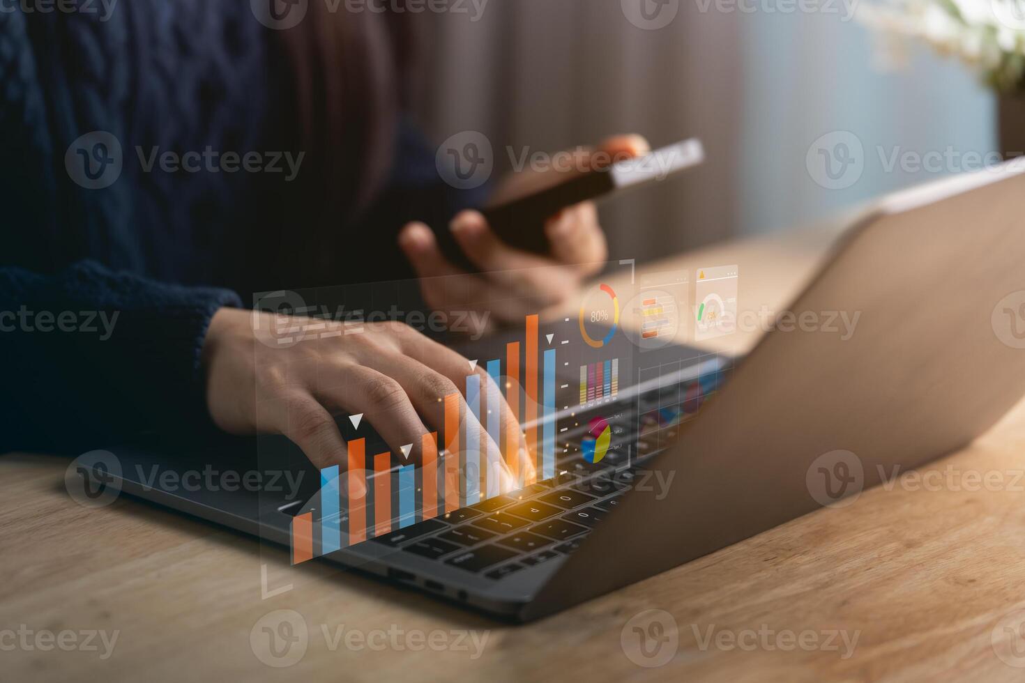 Close-up woman hand engaged in data analysis using a laptop and smartphone in a contemporary workspace, featuring charts and graphs for business insights. photo