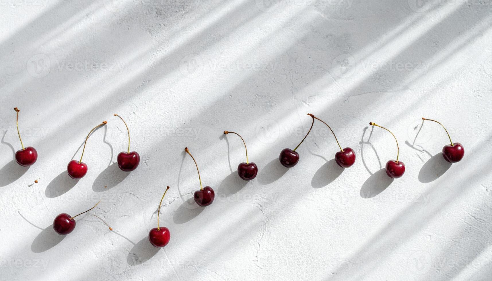 Studio still life of cherry stems linked end to end forming a wave on light concrete, thin shadow lines and modern graphic simplicity. photo
