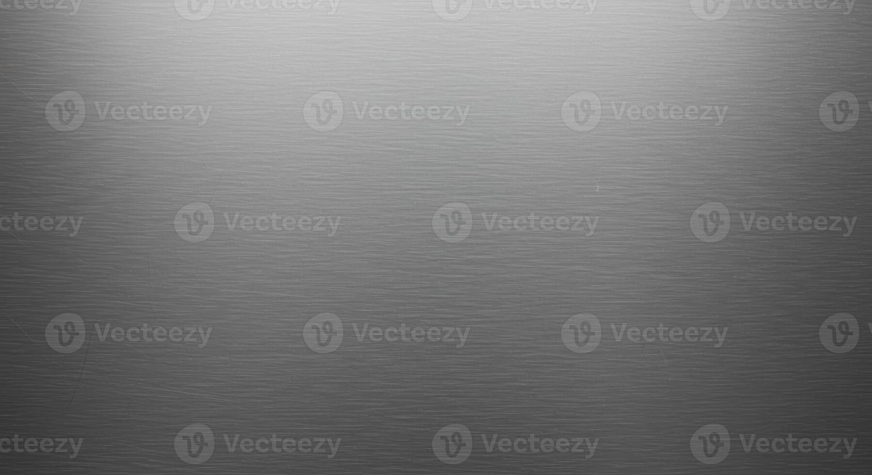 The subtle light reflects gently across the textured gray metallic background, creating a smooth gradient effect from bright on the left to dark on the right. photo