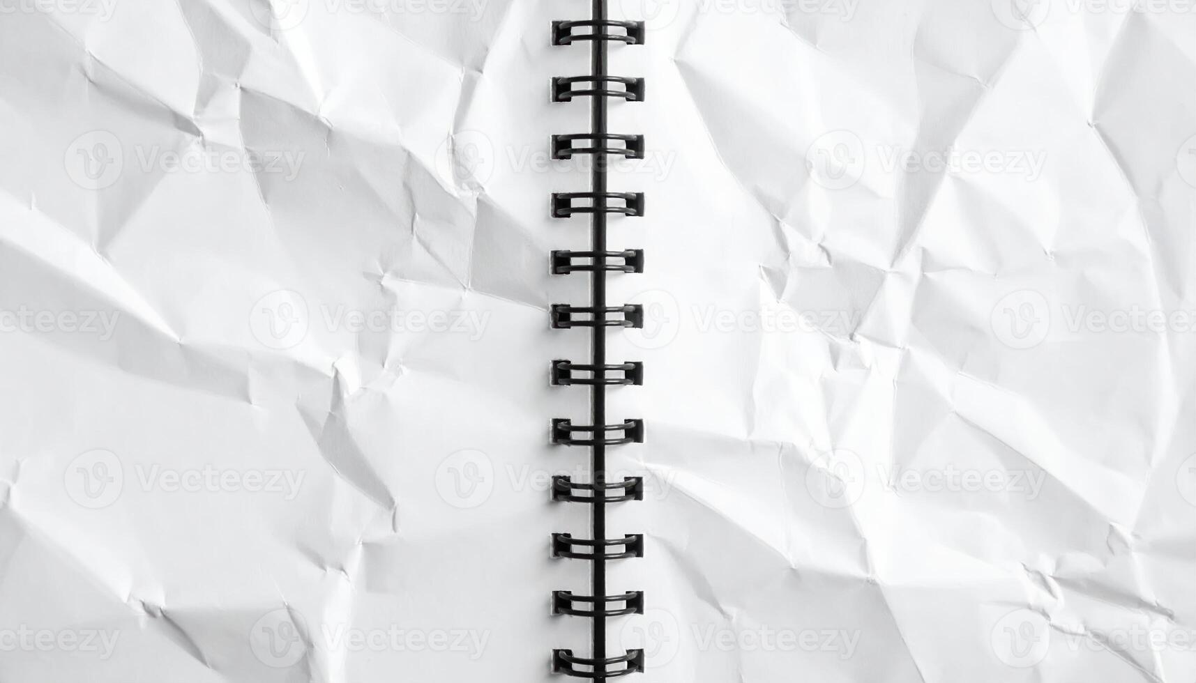 An open spiral bound notebook displays a crumpled white paper texture, creating a sense of creative chaos and potential for innovative ideas and design concepts. photo