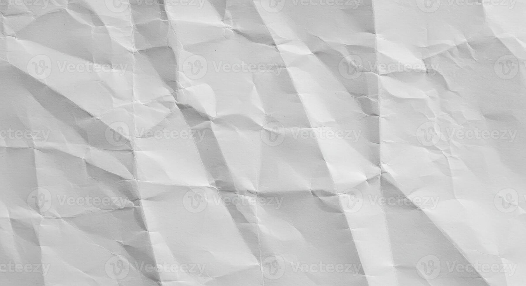 The heavily wrinkled and creased sheet of white paper creates a textured surface perfect for backgrounds and adding depth to graphic designs and illustrations. photo