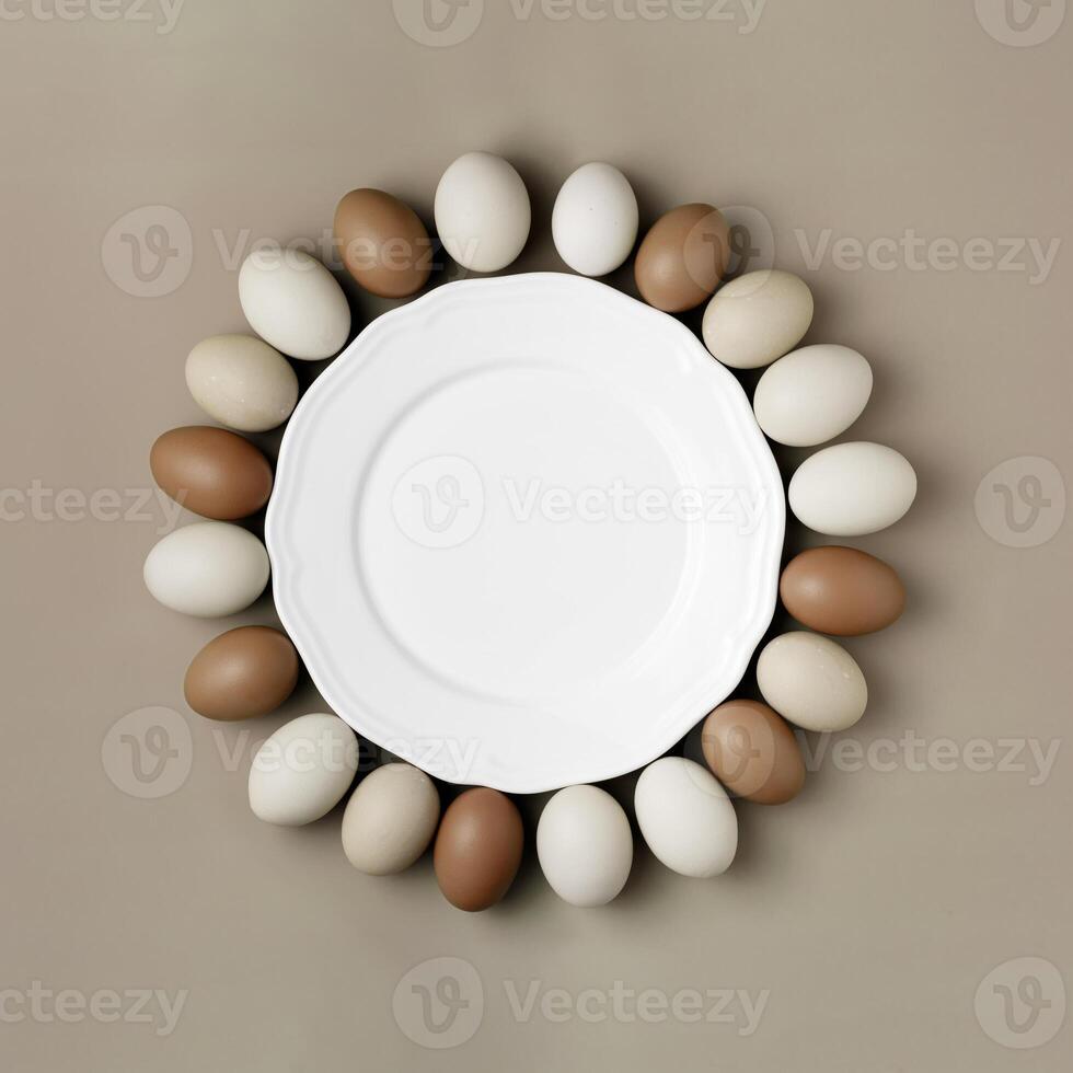 Top view of chicken eggs around white empty plate as copy space. Food round frame for national eggs day. Minimal style natural brown eggs on colored background. Monochrome gradient brown photo