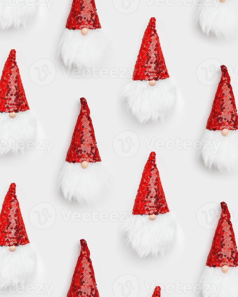 Christmas minimal style pattern with funny dwarfs with white beard. New Year bauble dwarf in shiny cap red colored on white. Happy New Year and Merry Christmas vertical background, top view photo