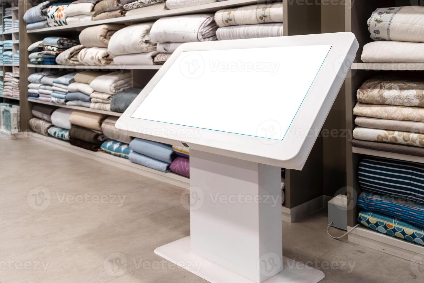 Digital display mock up with blank screen in a retail store showcasing neatly stacked textiles and blankets, providing a modern shopping experience with copy space photo