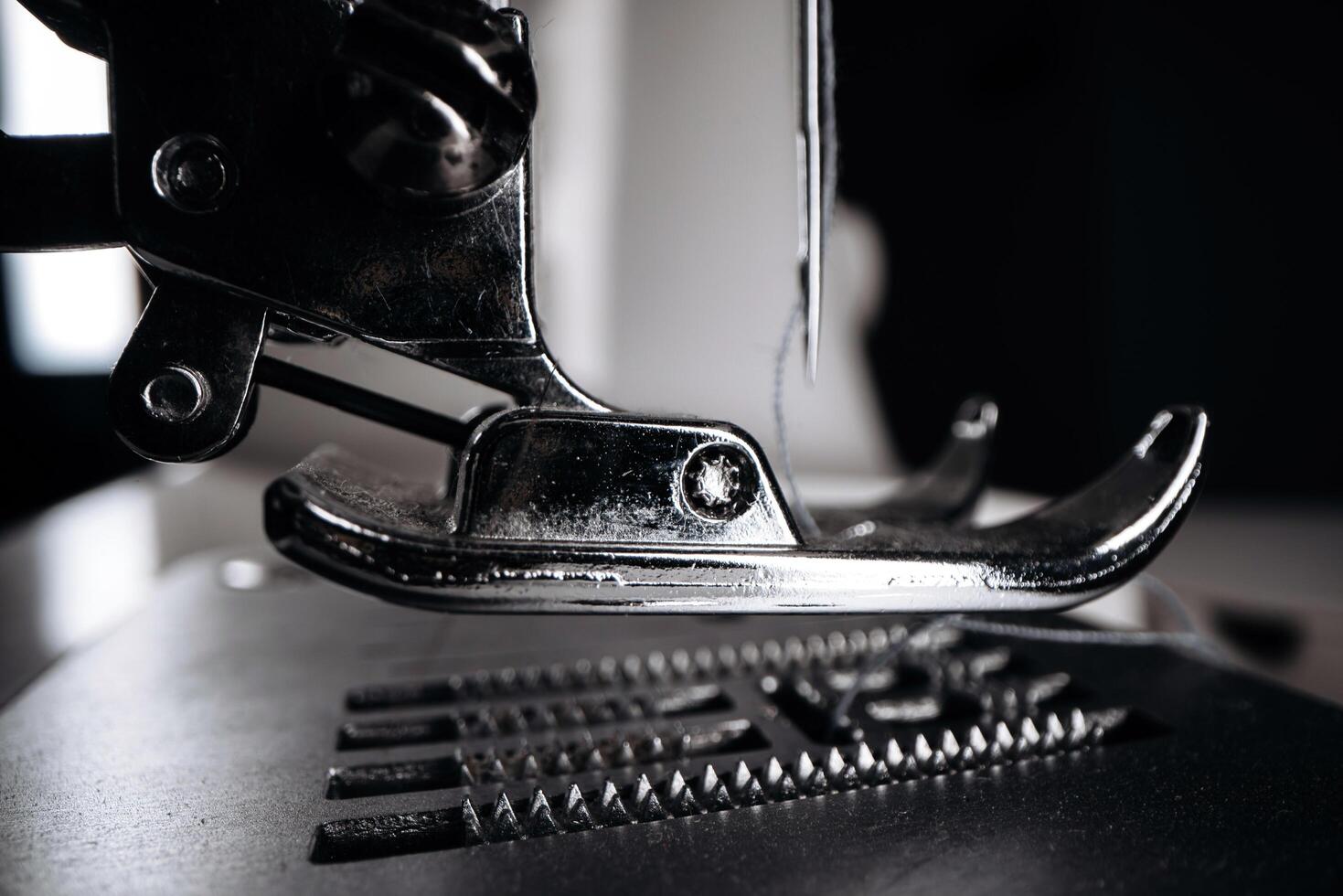 Close-up view of a sewing machine foot pressing down on fabric, showcasing intricate stitching patterns and the precision of textile craftsmanship in a well-lit workspace photo