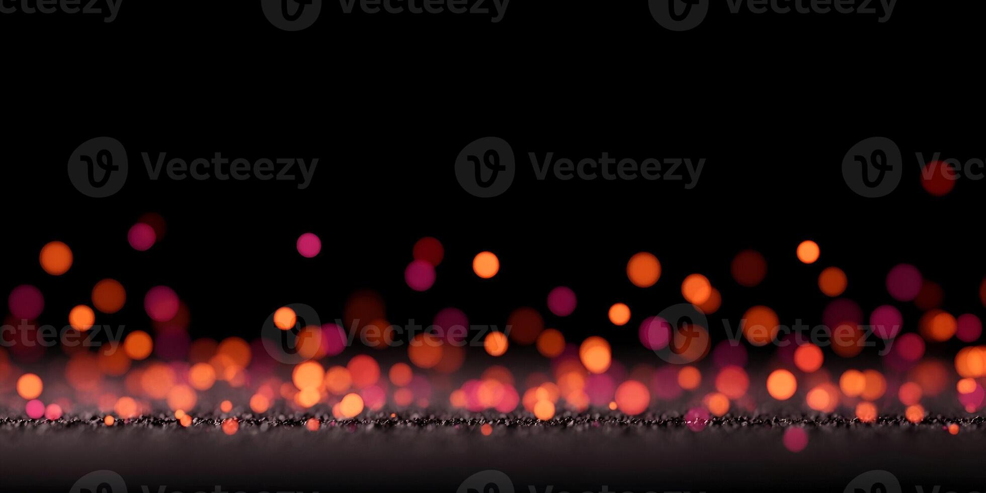 Numerous vibrant orange red and pink bokeh lights float over a dark textured surface creating a festive abstract background photo