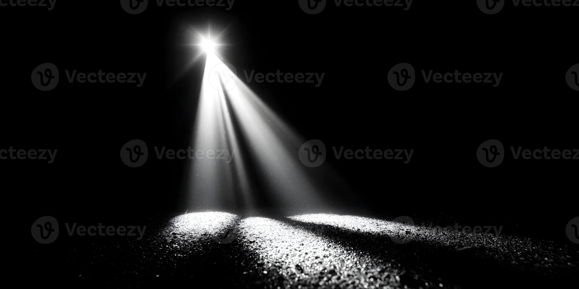 Bright white light dramatically shines from above creating strong rays and illuminating a textured floor in a dark empty space photo