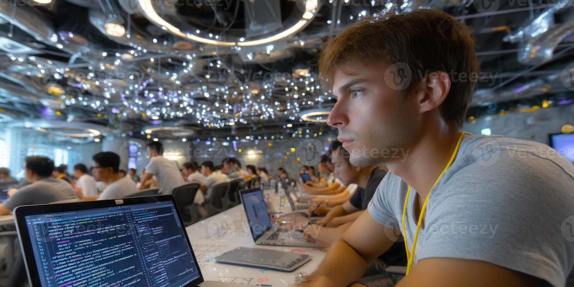 A focused developer codes on a laptop in a modern, well-lit workspace with colleagues. photo