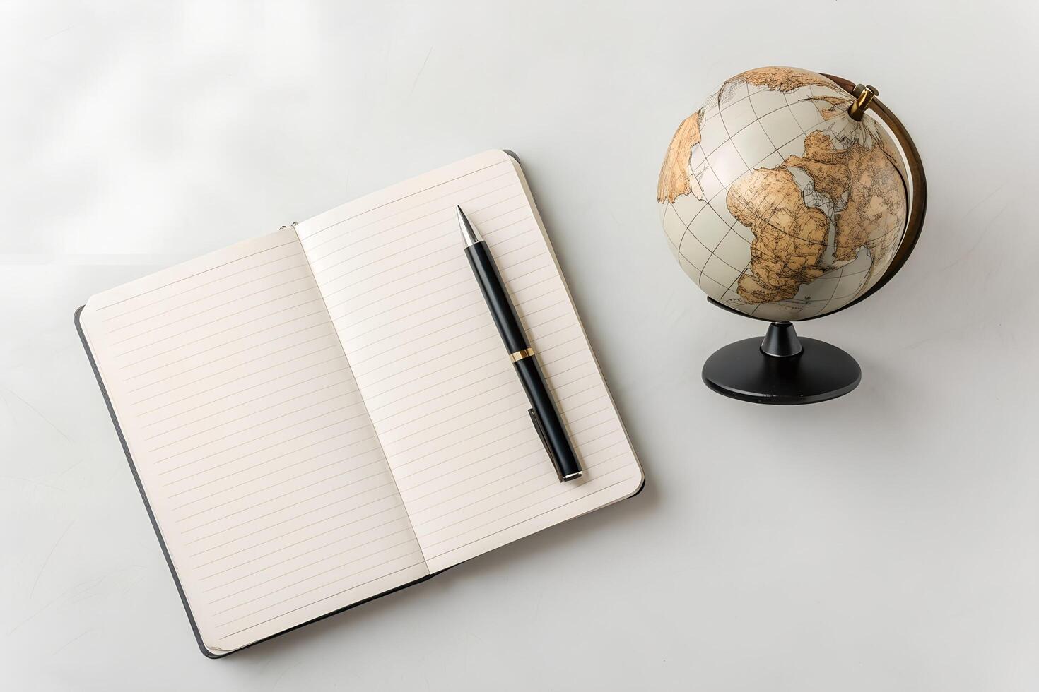 Overhead View of Open Dot Grid Notebook with Pen and Desktop Globe on White Background photo