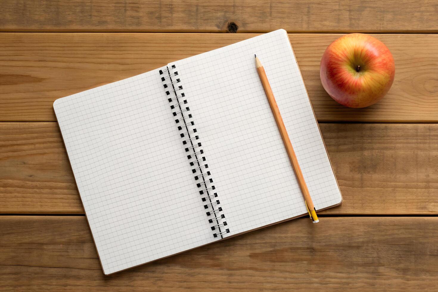Overhead View of Open Notebook with Pencil and Apple on Rustic Wooden Table photo