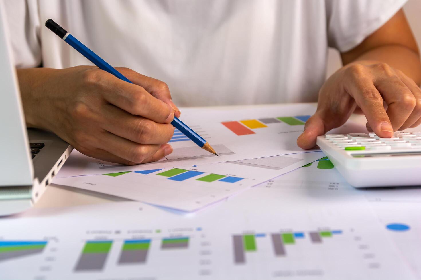 Hand writes down something while using calculator, using at the laptop at home for study, audit, remote work, accountant, calculator, count, business, work from home concept. photo