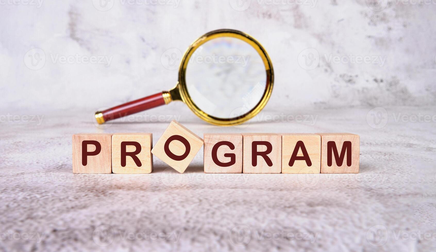 The concept word PROGRAM is collected of wooden cubes with a magnifying glass in the background .Loyalty Program Shopping concept photo