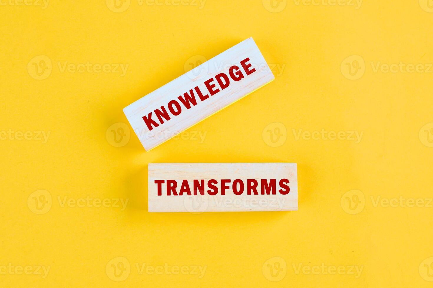 KNOWLEDGE TRANSFORMS concept words assembled from blocks on yellow background, top view photo