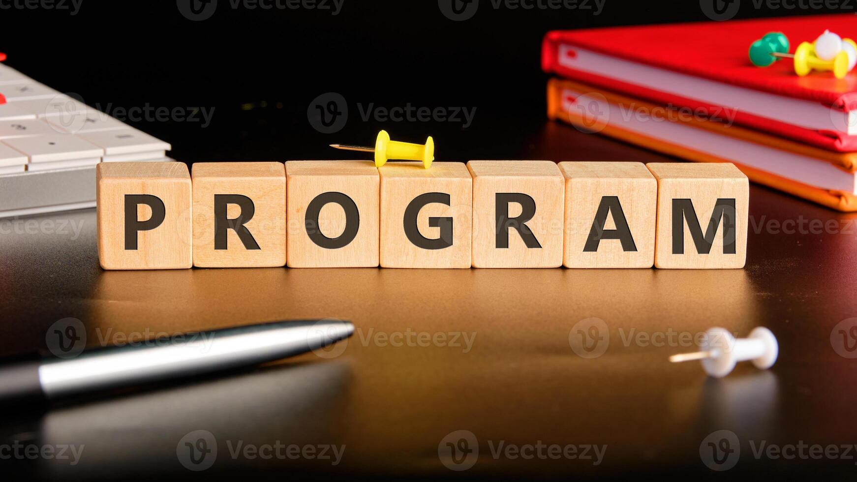 The concept word PROGRAM is collected of wooden cubes on a black background with stationery next to it. Loyalty Program Shopping concept photo