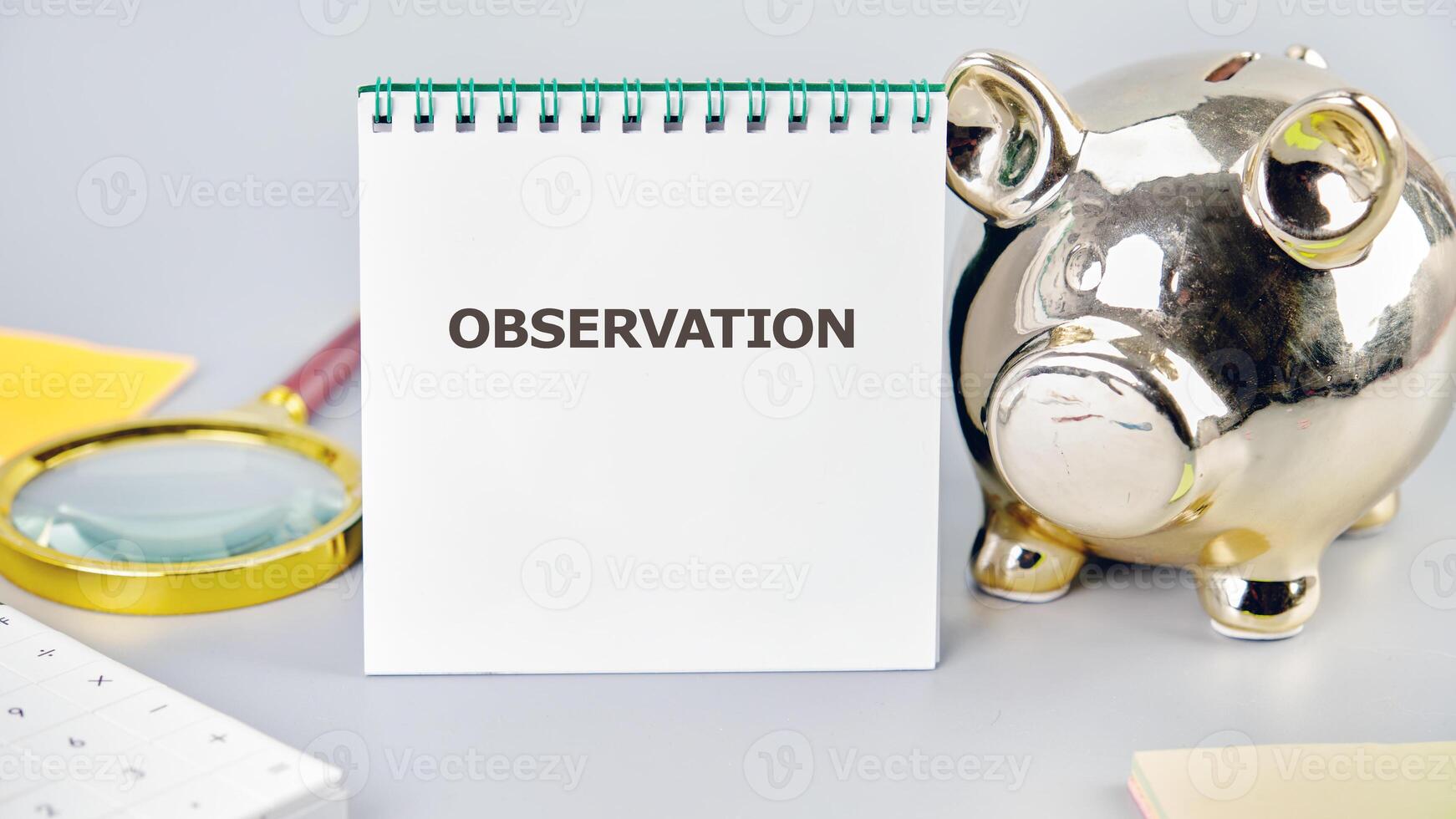 OBSERVATION word written in a notebook in a composition with a piggy bank and a magnifying glass. Observation concept image photo