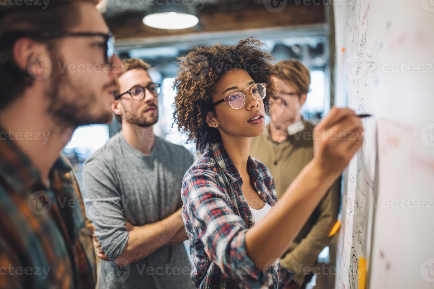 Team members are engaged in a brainstorming session in a garage, with one individual actively drawing on a large sheet of paper to illustrate ideas and concepts during the discussion photo