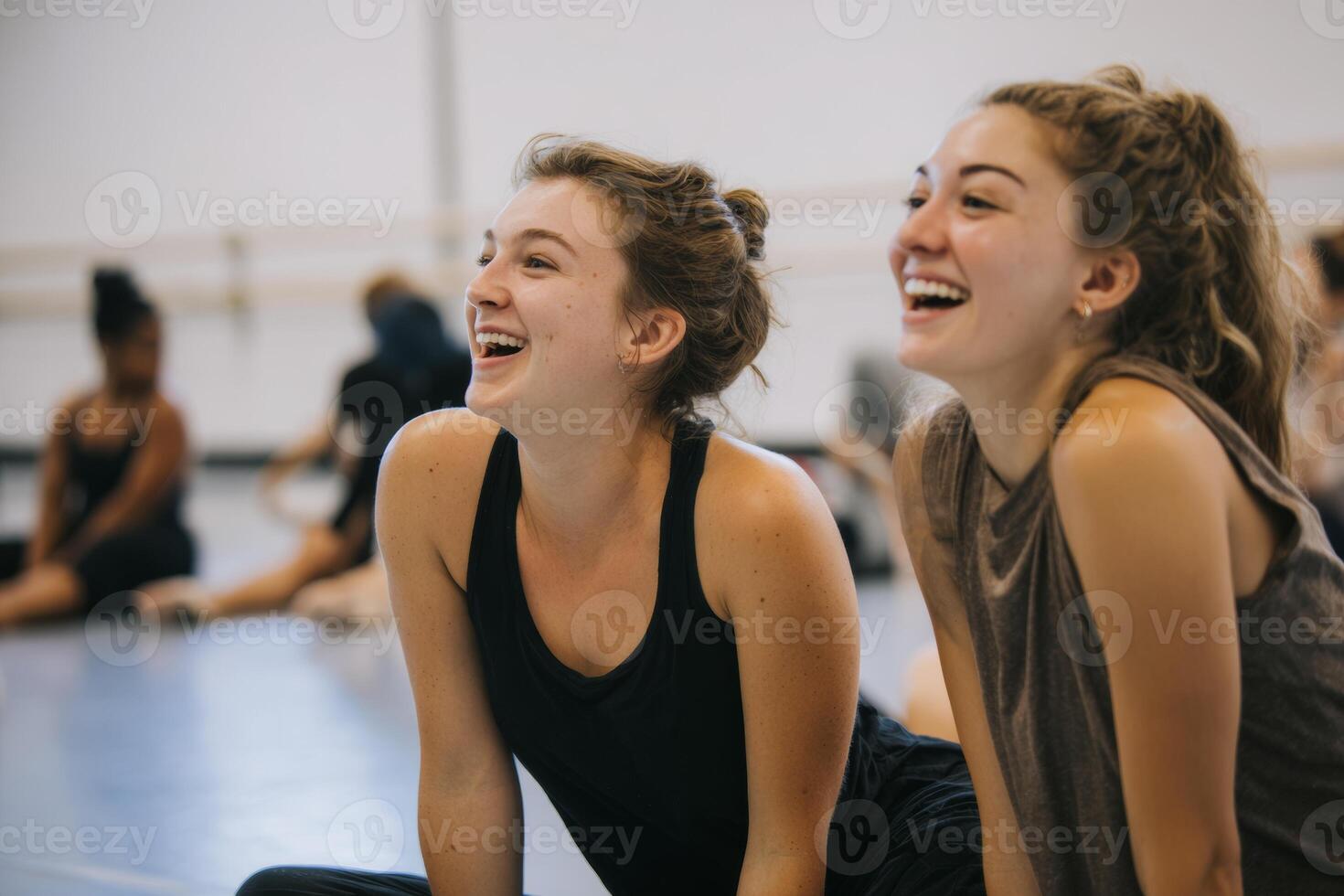 In a vibrant studio, dancers are engaged in a warm up session, laughing and stretching together on the floor, fostering a joyful and supportive environment photo