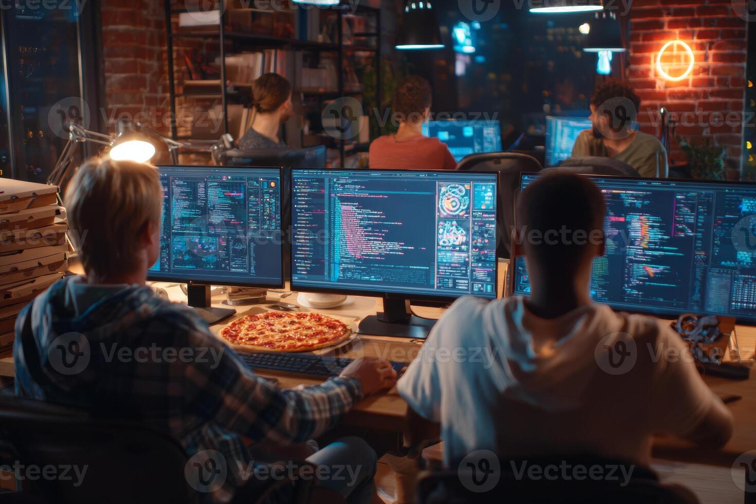 A group of engineers works late into the night testing software in a cramped home workspace. Multiple monitors display code and data, while pizza boxes hint at long hours spent together photo