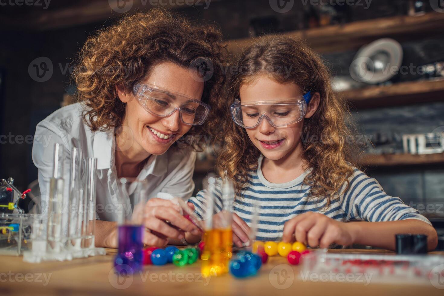 A parent and child are joyfully collaborating on a science project while participating in a virtual lesson. Colorful experiment materials are neatly spread on their work table photo