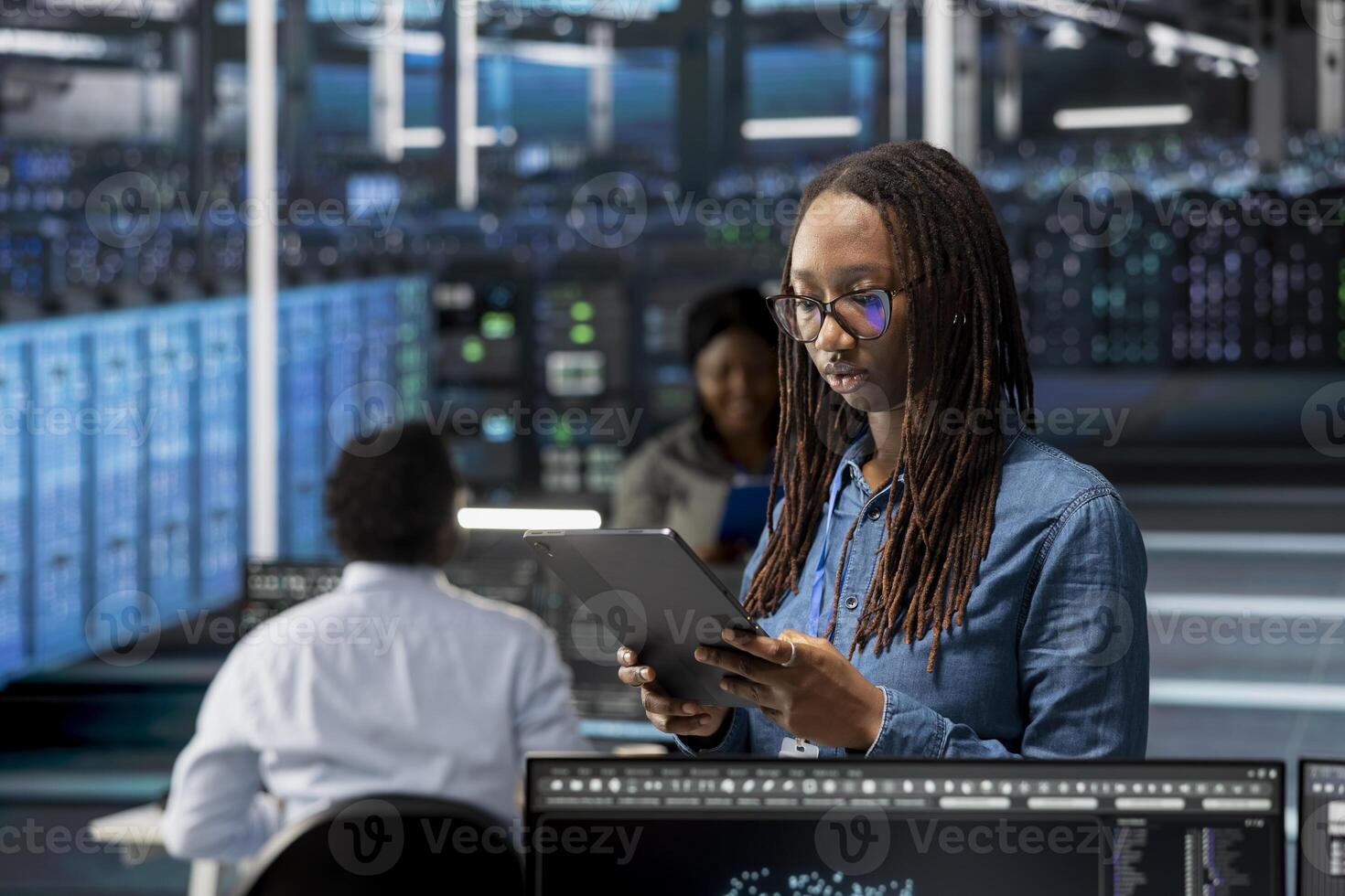 Data center admin using tablet to monitor system performance, identifying bottlenecks. Woman in server room using device to troubleshoot errors, implementing optimizations photo