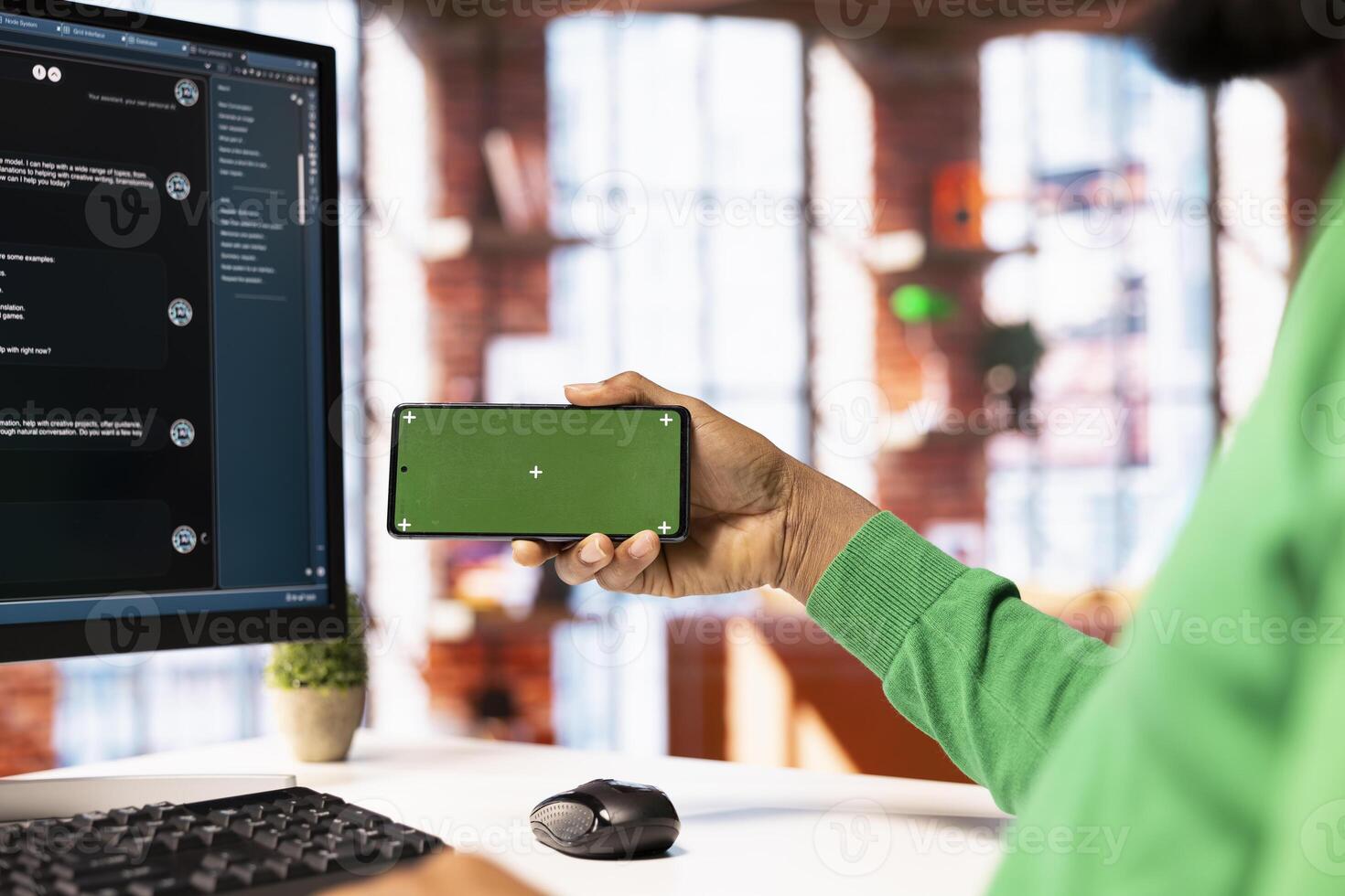 Man at desk watching on isolated screen phone about how to use AI LLM chatbot software. Person looking at tutorials on chroma key smartphone learning how to use large language model program photo
