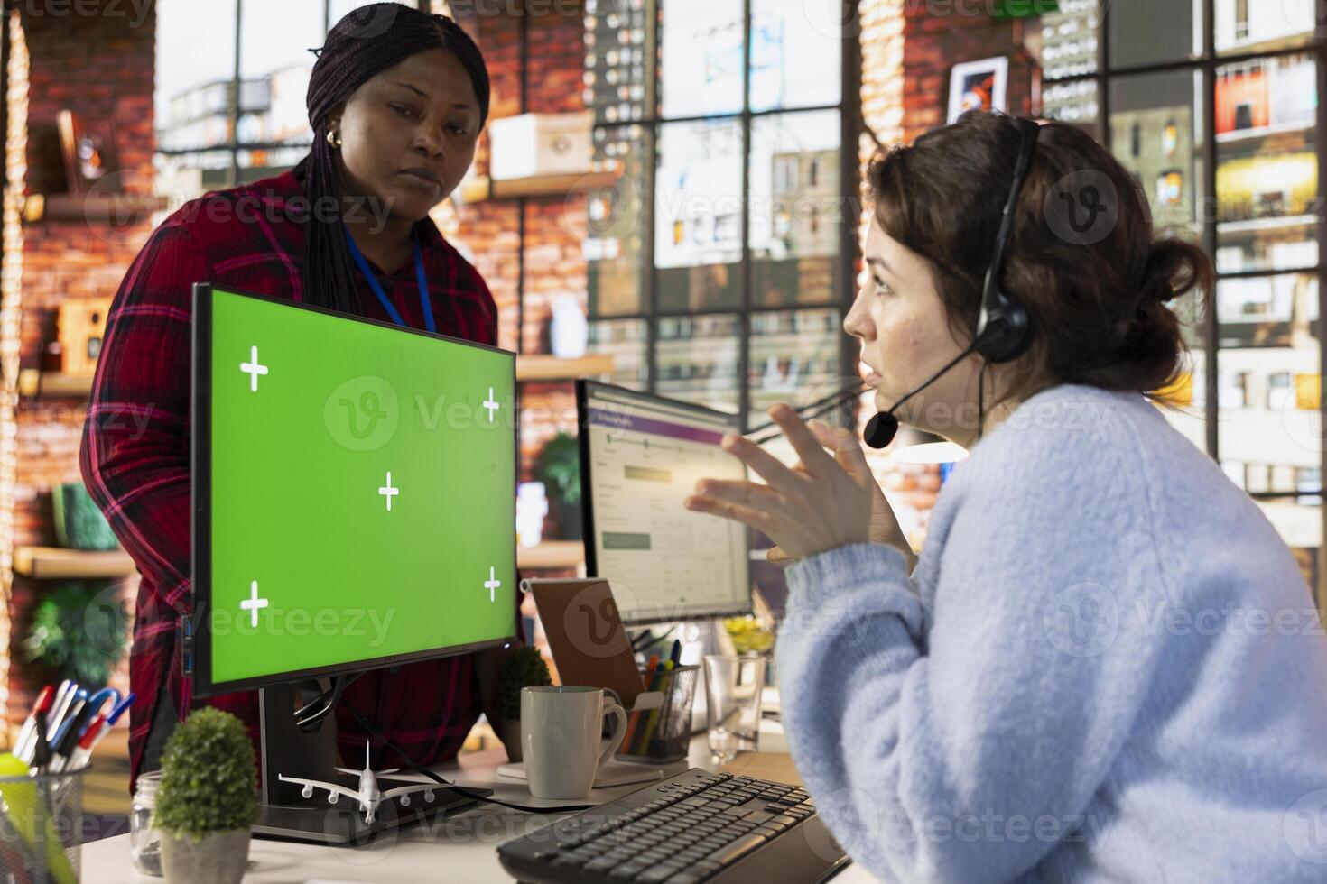 Call center onboarding specialist training new recruit using green screen computer. Supervisor in customer support department office showing intern how to use company application using chroma key PC photo