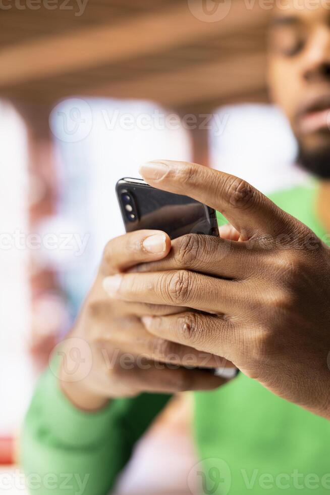 Man at home browsing internet on mobile phone, researching information online. Person in apartment using search engine on smartphone device to find relevant info, close up shot photo