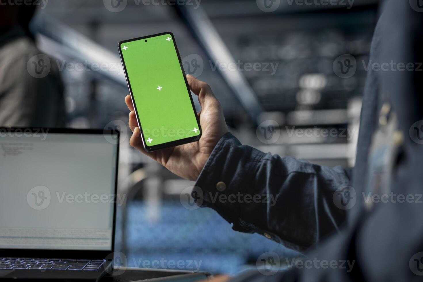 Close up of server farm software developer using mockup phone, waiting for code to finish compile. Data center employee checking mobile apps on green screen smartphone to relax photo
