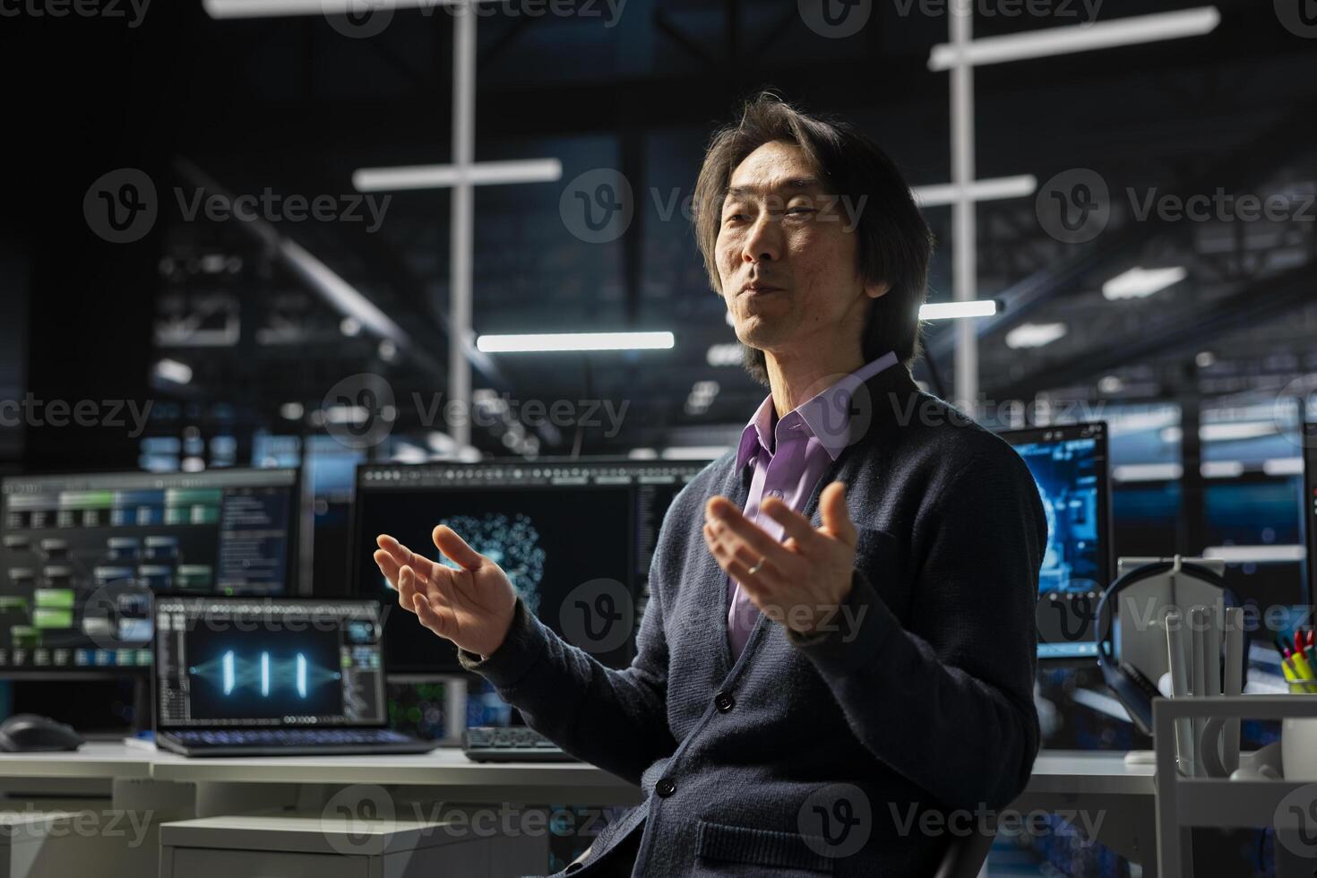 Computer scientist in server room using device to review infrastructure diagnostics. Asian senior programmer in high tech data center analyzing performance data to maintain system uptime photo