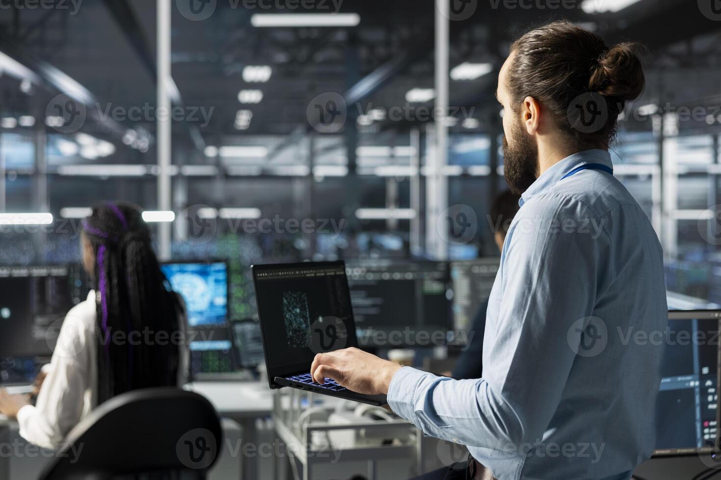 Data center engineer working on databases supporting AI apps using laptop. IT employee in server room using artificial intelligence technology to do algorithms improvements photo