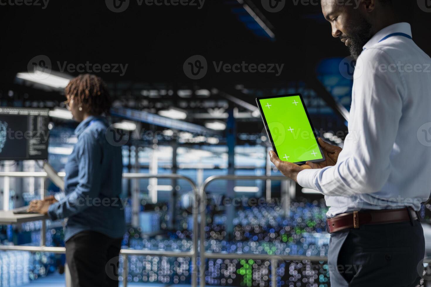 African american technician using copy space display on tablet, solving software development tasks on industrial platform. Young man visualizing infrastructure engineering in server room. photo