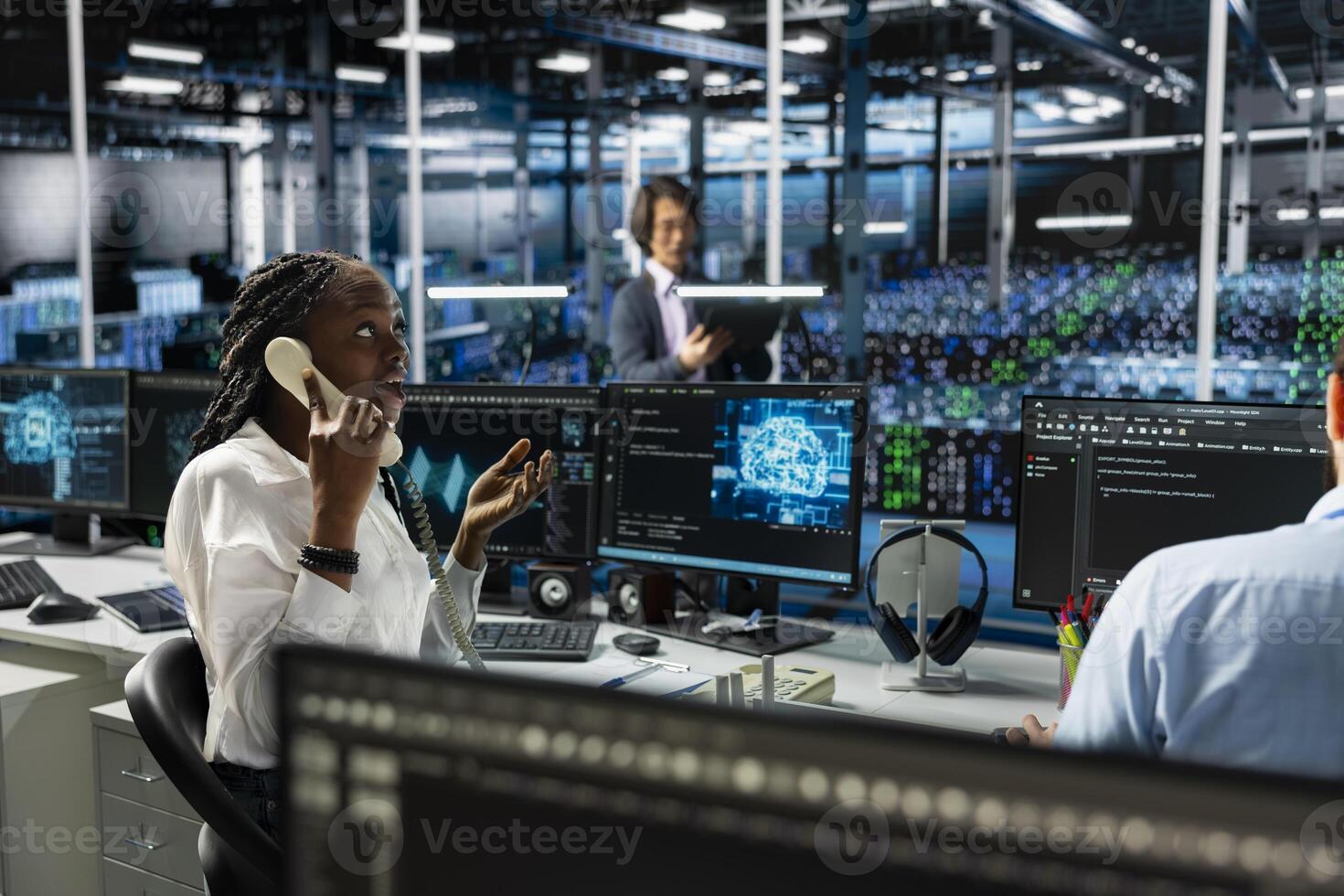 Admin in data center answers telephone call, assisting users with AI troubleshooting. Server farm IT specialist talks in phone call, managing clients issues using artificial intelligence photo