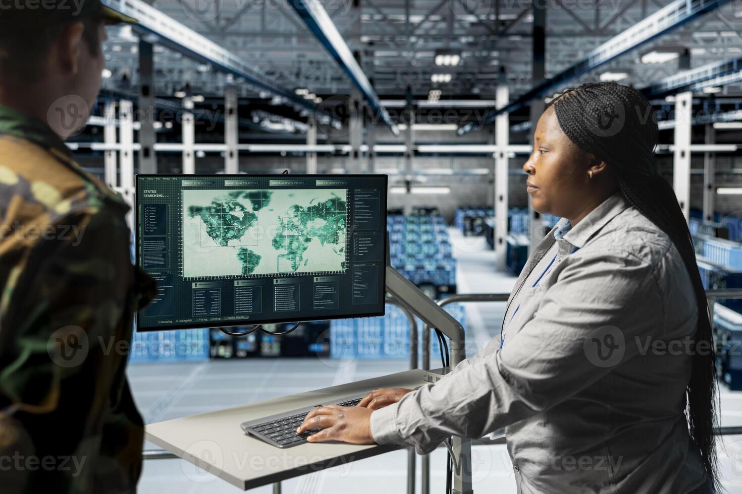Military expert talking with data center command officer, looking at world map on monitor, analyzing target coordinates. African american woman in server farm and commander looking at global map photo
