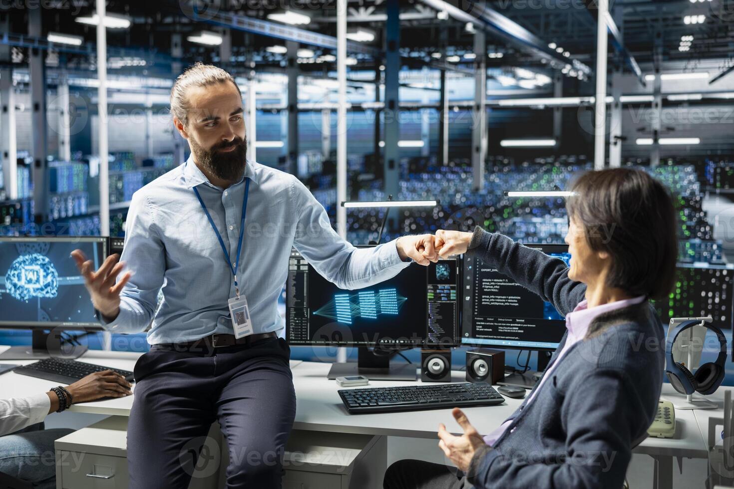 Coworkers coding in data center doing fist bump, pleased after updating AI automation scripts. Happy server room colleagues celebrating programming artificial intelligence algorithms photo