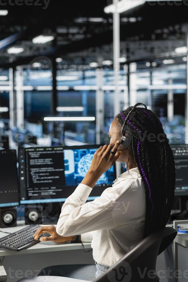 Data center operator providing user technical support, conducting remote diagnostics. Server farm IT expert managing live support calls, identifying hardware issues using predictive AI alerts photo