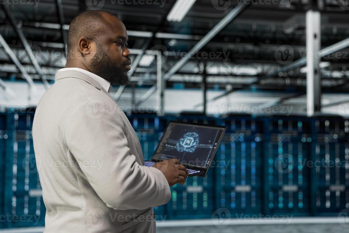 Data center system administrator using artificial intelligence computerized model on laptop. African american server room worker working with AI machine learning algorithms on device photo