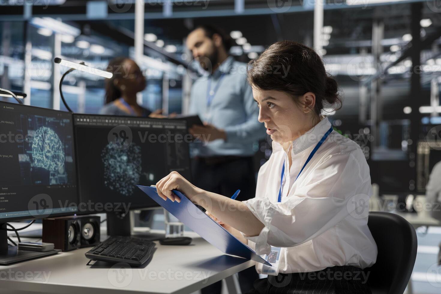 Server room worker looking at AI visualization charts, reviewing documentation on clipboard ahead of audit. AI data center expert verifying configuration data and compliance standards at desk photo