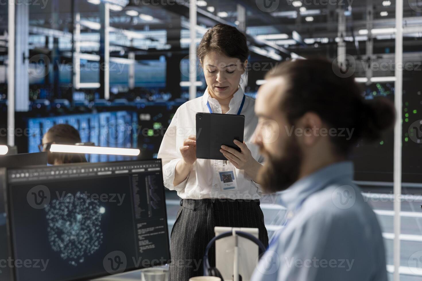Admin in data center using tablet to update storage arrays software, configuring network virtualization. Woman in server room using device to verify settings, maintaining stable performance photo