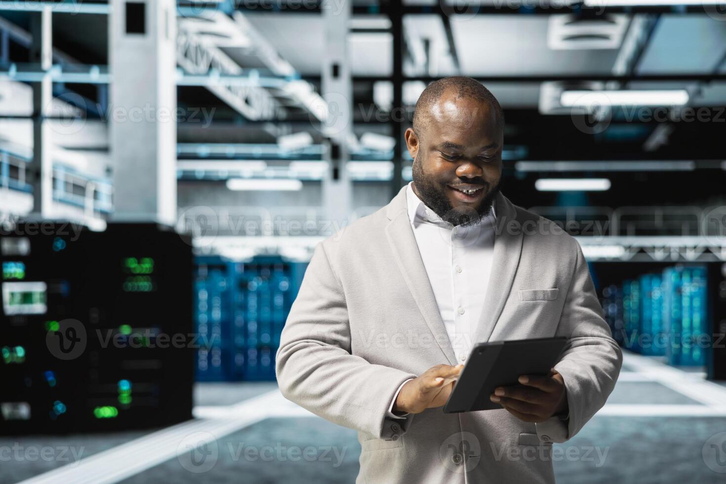 Happy data center engineer writing lines of code running on tablet, troubleshooting rackmounts. Cheerful IT professional using programming scripts on device in server room photo